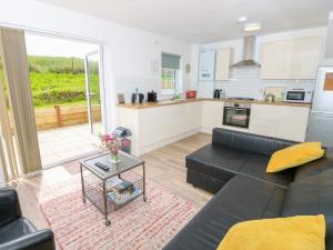 ein Wohnzimmer mit einer schwarzen Couch und einer Küche in der Unterkunft 6 Yarmouth Cottages in Freshwater + 20 Fotos