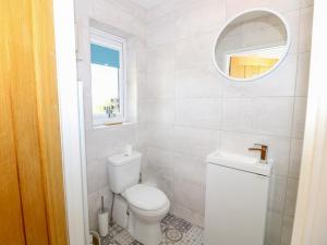 ein weißes Bad mit einem WC und einem Spiegel in der Unterkunft 6 Yarmouth Cottages in Freshwater