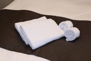 a bed with two towels and two rolls of towels at HOTEL PROMOTE HIROSHIMA in Hiroshima