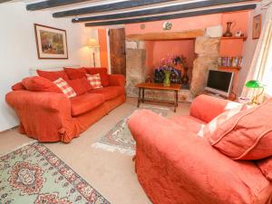 彭贊斯的住宿－The Thatched Cottage，客厅配有2张橙色沙发和壁炉
