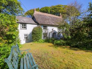 彭贊斯的住宿－The Thatched Cottage，白色房子前面的绿色长凳