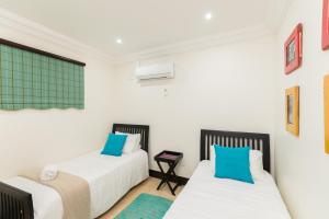 a bedroom with two beds with blue pillows at Ballito Manor - Manor View 102 in Ballito