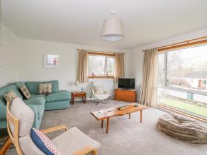 a living room with a green couch and a table at Cromallt in Aberfeldy