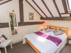 een slaapkamer met een bed, een stoel en een spiegel bij Old Stables Cottage in Saltburn-by-the-Sea