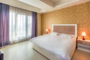 a bedroom with a large white bed and a window at Diplomat Suites in Baku