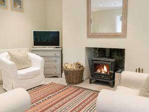 a living room with a fireplace and a tv at Gate Lodge in West Calder