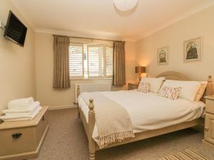 um quarto com uma cama grande e uma janela em Meadowlea Cottage em Plymouth