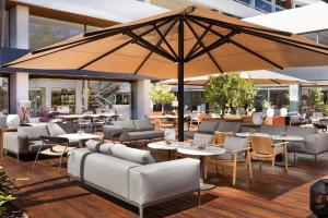 a patio with couches and tables and a large umbrella at Hotel Don Pepe Gran Meliá in Marbella