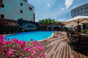 a swimming pool with tables and umbrellas and flowers at Lao Cai Star Hotel in Lao Cai