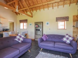 a living room with two purple couches and a kitchen at Y Bwthyn in Llanfairpwllgwyngyll