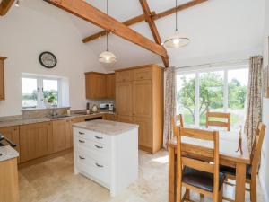 een keuken met houten kasten en een tafel en stoelen bij Golden Valley Barn in Bristol