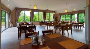 Un restaurante con mesas y sillas y grandes ventanales. en Pensjonat Olympia w Przesiece, en Przesieka