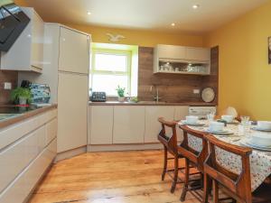 cocina con mesa, sillas y nevera en Gadlys House - Beau View, en Beaumaris