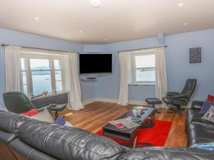a living room with a leather couch and a flat screen tv at Gadlys House - Beau View in Beaumaris