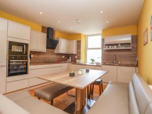 a kitchen with a wooden table and a dining room at Gadlys House - Waters Edge in Beaumaris