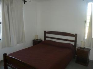 a bedroom with a bed with two night stands and two windows at Maga in Piriápolis