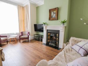 a living room with a fireplace and a tv at Newbegin Cottage in Hornsea