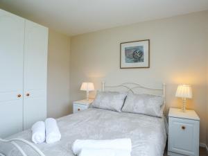 a white bedroom with a bed and two night stands at Garreg Wen in Criccieth