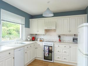 a kitchen with white cabinets and a window at Garreg Wen in Criccieth