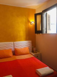 a bedroom with a bed with orange sheets and a window at DiVino Marsala centro in Marsala