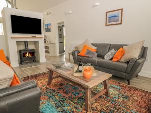 a living room with couches and a table and a fireplace at Cowslip in Bamburgh
