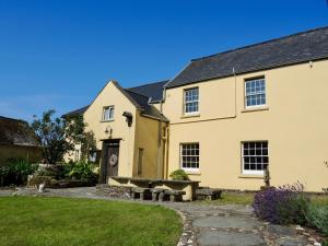 una casa amarilla con un banco delante en Holwell Holistic Retreat en Barnstaple