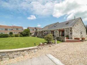 a stone house with a stone wall and a yard at Woodside Barns in St Austell
