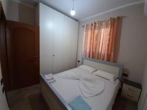 a small bedroom with a bed with white sheets at Apartment Demaj in Vlorë