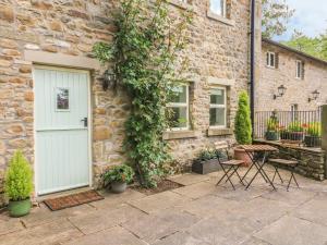 a stone house with a white door and ivy at Spens Farm Cottage in Lancaster