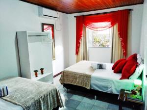 1 dormitorio con 2 camas y una ventana con cortinas rojas en Gardenia House, en Foz do Iguaçu