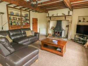 a living room with a leather couch and a fireplace at Dale View in Skipton