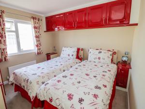 a bedroom with two beds and red cabinets at Booster's Lodge in Stratford-upon-Avon