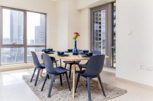 a dining room with a table and chairs and windows at Quintessential Quarters - Ultra-modern and Spacious Aparment in Dubai