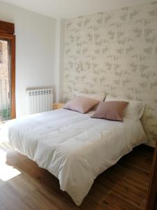 1 dormitorio con 1 cama blanca grande con almohadas rosas en Apartamentos La Réunion en Camarena de la Sierra