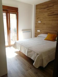 1 dormitorio con 1 cama grande y pared de madera en Apartamentos La Réunion, en Camarena de la Sierra