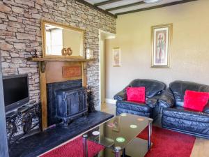 a living room with two leather couches and a fireplace at Minydon in Fairbourne