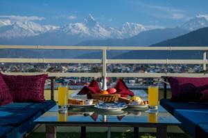 uma mesa com comida no topo de uma varanda com montanhas em Hotel Task International em Pokhara