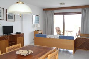 a living room with a dining room table and a television at Apartamentos Marina in Port de Pollensa
