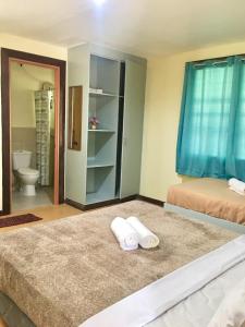 a room with two beds and a bathroom with a toilet at Johann’s Place Panglao in Panglao