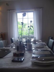 une grande table avec des fleurs et une fenêtre dans l'établissement Aaron Glen Guest House, à Loanhead