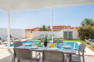 Un patio con mesa y sillas y una piscina. en Villa 26, en Cala'n Bosch