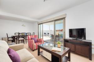 Una sala de estar con un sofá y un televisor. en Villa 26, en Cala'n Bosch