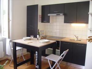 a kitchen with a table with two chairs and a sink at Hôtel du Clos Fleuri in Lourdes