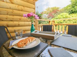 una mesa con un plato de pan y un jarrón con flores en Willow Lodge, en Tenby