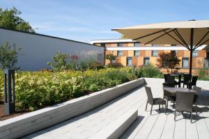 eine Terrasse mit einem Tisch, Stühlen und einem Sonnenschirm in der Unterkunft Hotel Franz in Essen