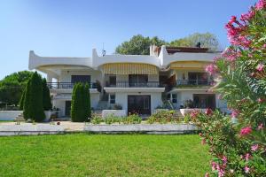 a large white house with flowers in the yard at Villa Vasiliki in Paralía Avdhíron