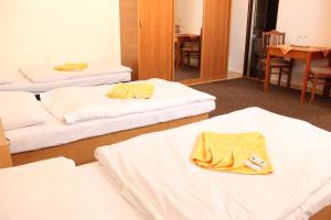 um quarto com três camas com lençóis brancos em Penzión Zlatý Dukát em Zvolenská Slatina