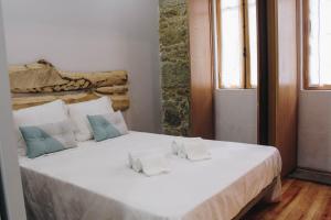 
a bed with white sheets and pillows in a room at Siglas & Runas II in Póvoa de Varzim
