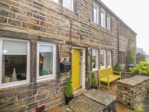 a brick building with a yellow door and a yellow bench at Fleece Cottage in Holmfirth