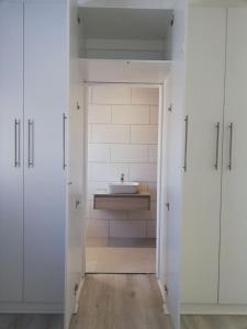 a bathroom with a sink and a white door with a sink at Milo's Sky Grey Guest House - No Load shedding in Cape Town